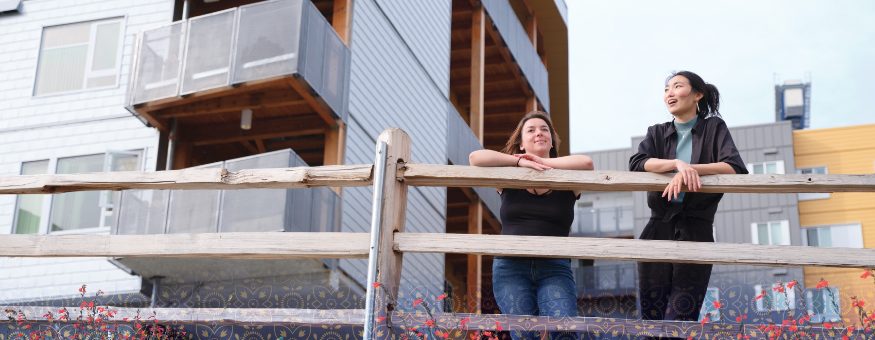 two people leaning on a fence