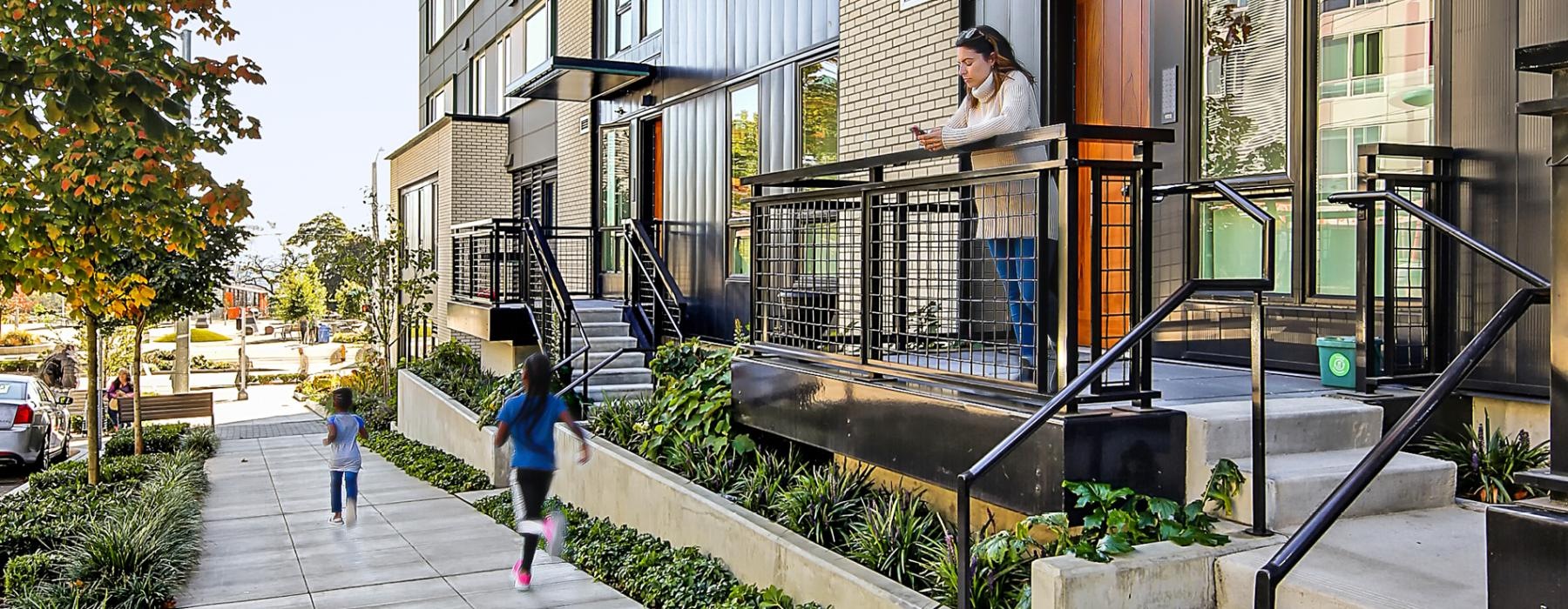 children run down sidewalk in front of apartments with private decks